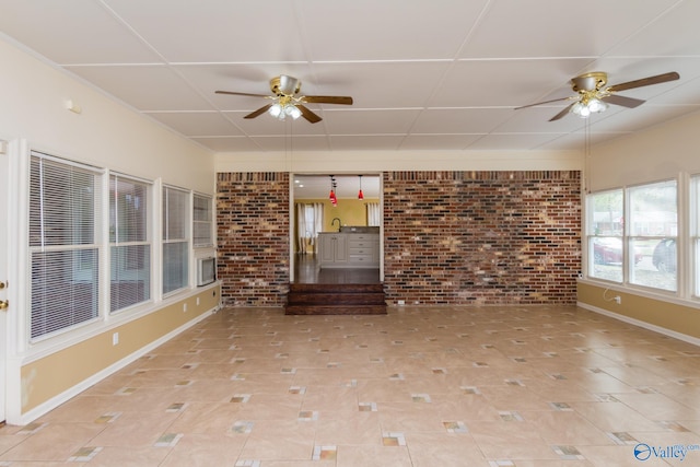 interior space featuring light tile patterned floors, ceiling fan, and brick wall