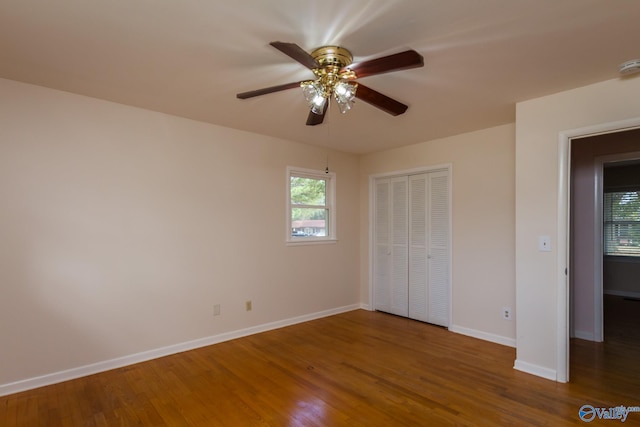 unfurnished bedroom with dark wood-type flooring, ceiling fan, and a closet