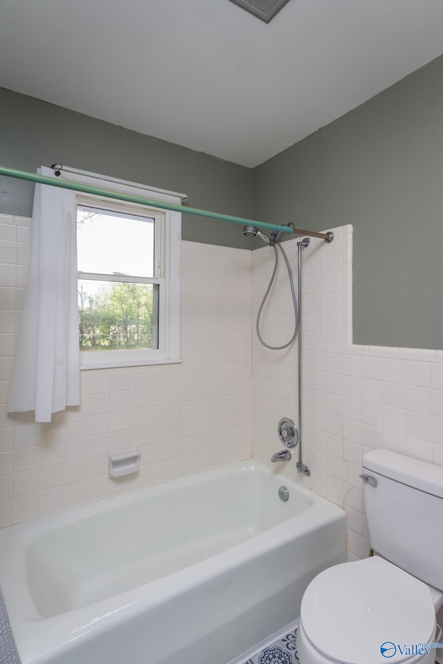 bathroom featuring toilet, tile walls, and tiled shower / bath