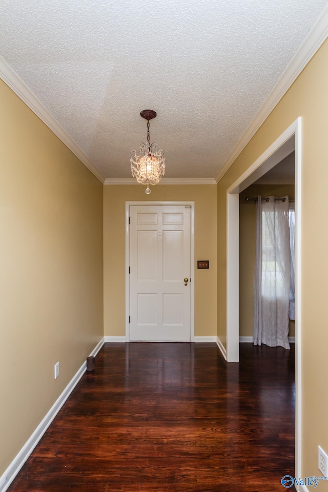 interior space with dark hardwood / wood-style flooring, a textured ceiling, a notable chandelier, and ornamental molding