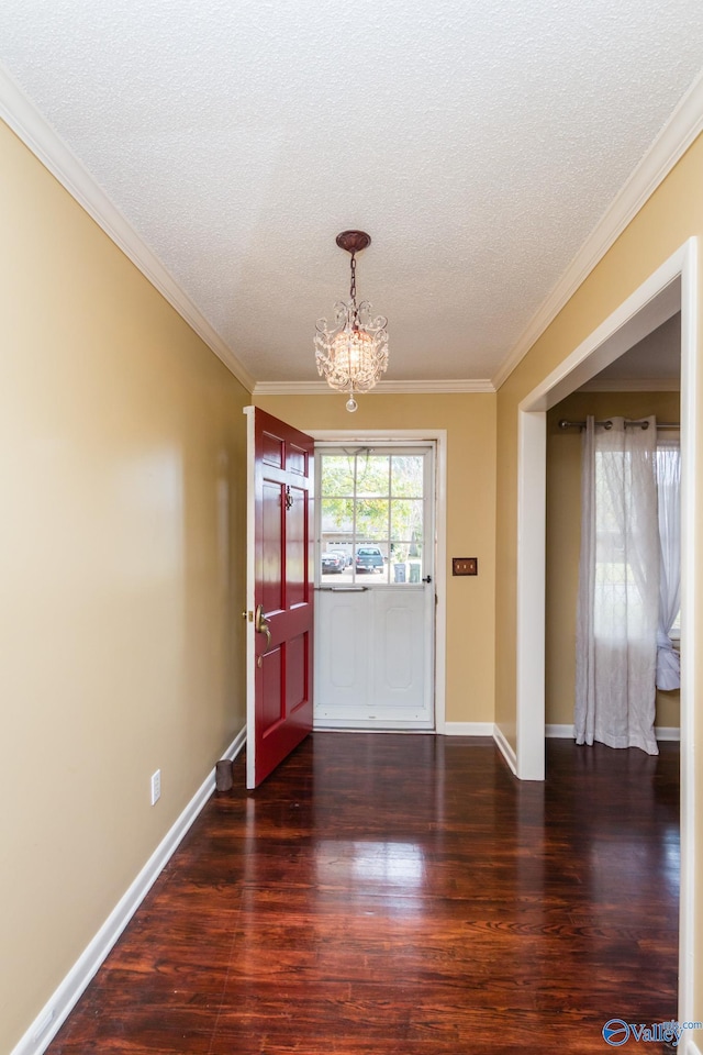 entrance foyer with ornamental molding, a textured ceiling, dark hardwood / wood-style flooring, and a notable chandelier