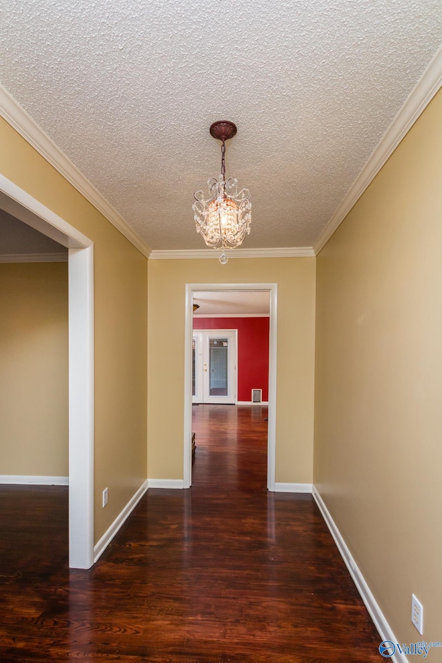 unfurnished dining area with dark hardwood / wood-style floors, a textured ceiling, a chandelier, and crown molding