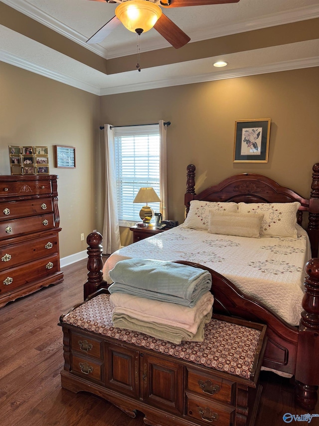 bedroom with a tray ceiling, crown molding, dark wood-type flooring, and ceiling fan