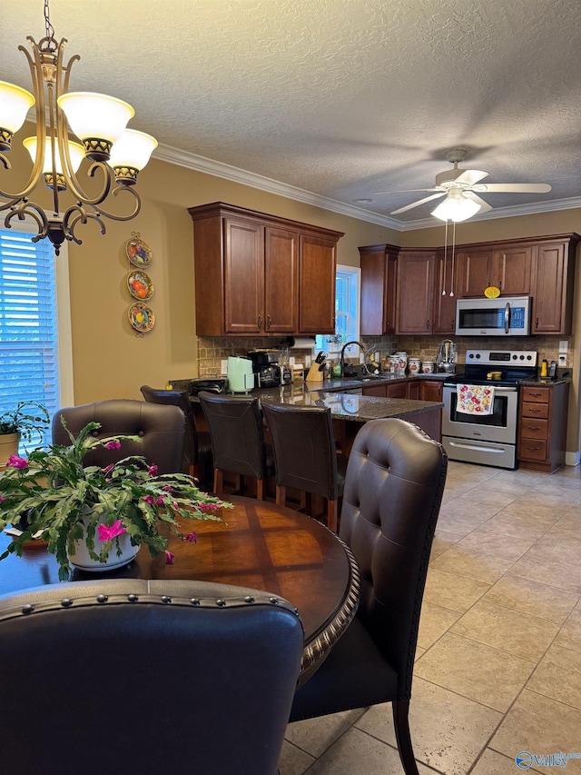 kitchen featuring hanging light fixtures, crown molding, stainless steel appliances, and a healthy amount of sunlight