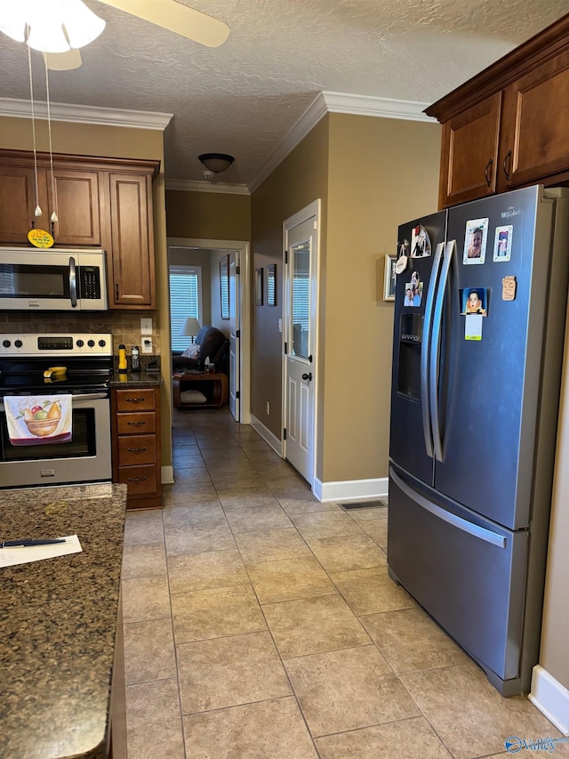 kitchen with dark stone countertops, ornamental molding, and stainless steel appliances