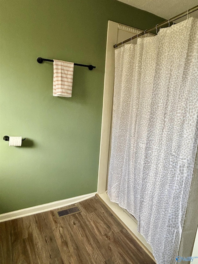 bathroom with hardwood / wood-style flooring, a textured ceiling, and walk in shower