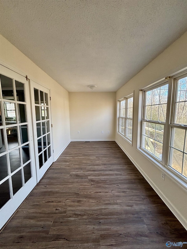 spare room featuring dark wood-type flooring, a textured ceiling, and french doors