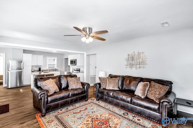living room featuring wood finished floors, visible vents, and ceiling fan