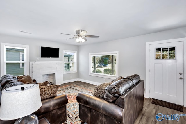 living area with dark wood finished floors, baseboards, visible vents, ceiling fan, and a fireplace