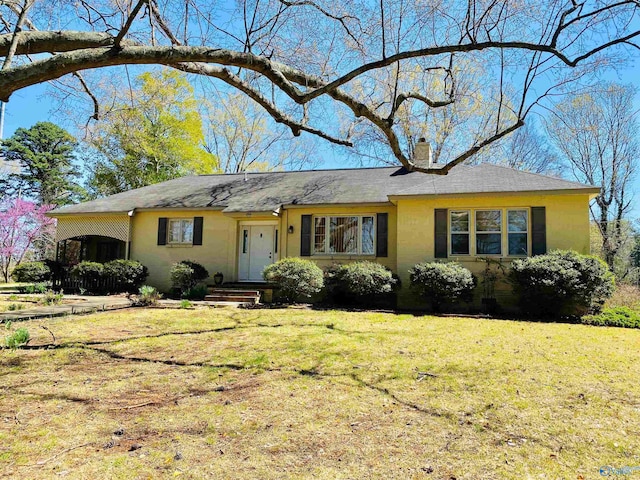 single story home featuring a chimney, a shingled roof, and a front lawn