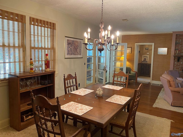 dining room featuring a textured ceiling, wood finished floors, a notable chandelier, and plenty of natural light