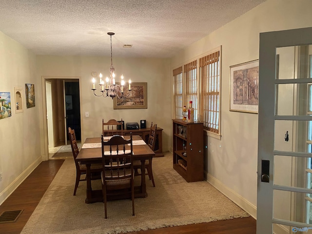 dining space featuring a chandelier, a textured ceiling, baseboards, visible vents, and dark wood-style flooring