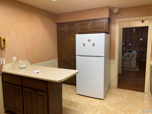 kitchen with light countertops, wallpapered walls, and freestanding refrigerator