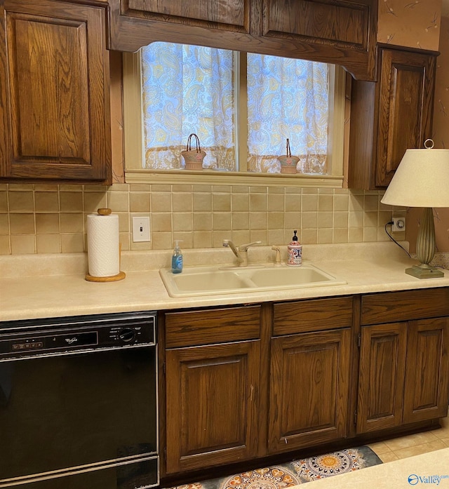 kitchen featuring dishwasher, light countertops, a sink, and tasteful backsplash