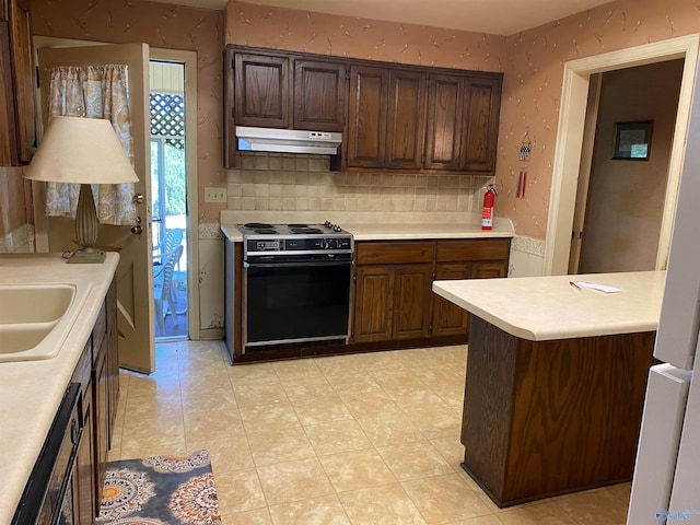 kitchen featuring under cabinet range hood, black electric range oven, wallpapered walls, and light countertops