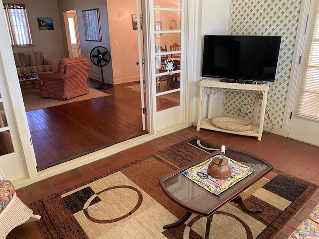living area with baseboards and brick floor