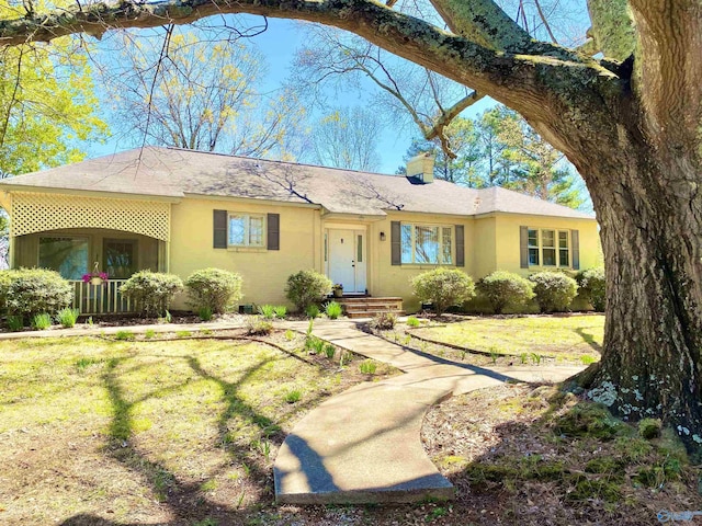 single story home with a front lawn, a chimney, and stucco siding