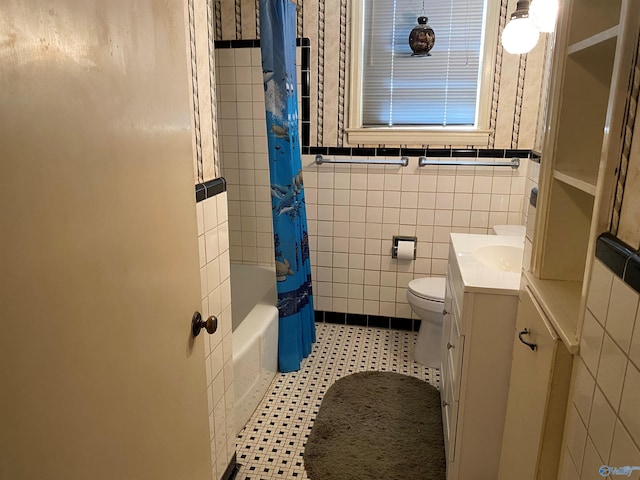 bathroom with toilet, vanity, shower / bathtub combination with curtain, and tile walls