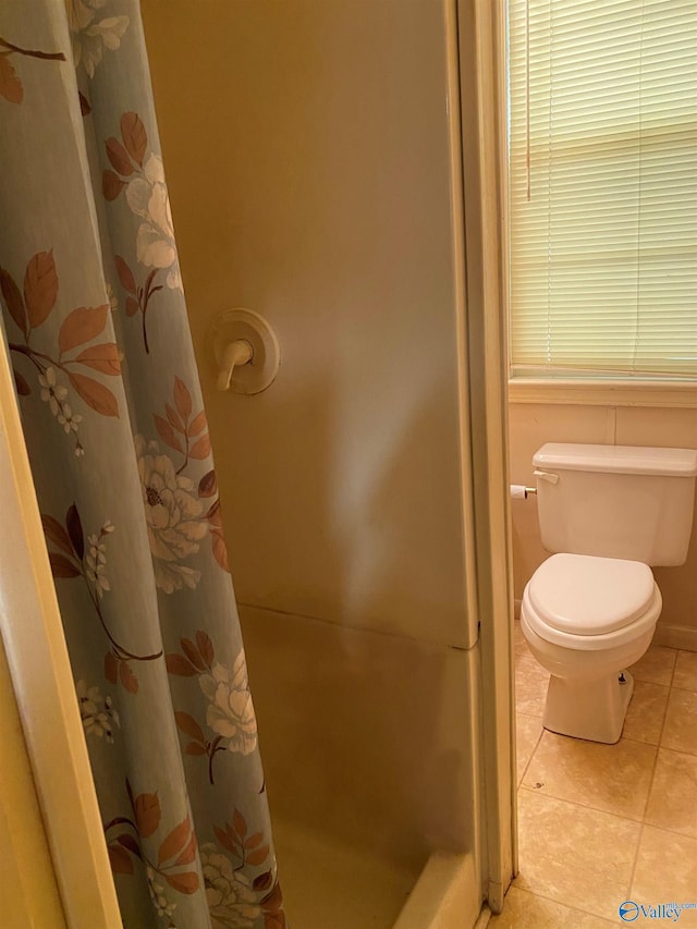 full bath featuring tile patterned floors, toilet, and curtained shower