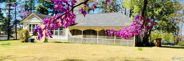 view of front of home with cooling unit and a front lawn