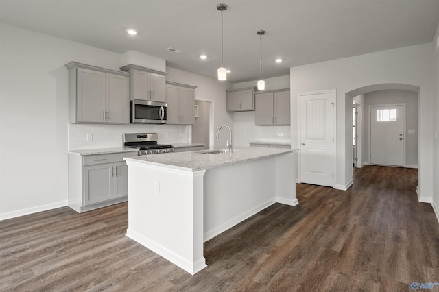 kitchen featuring gray cabinetry, a center island with sink, sink, light stone countertops, and appliances with stainless steel finishes