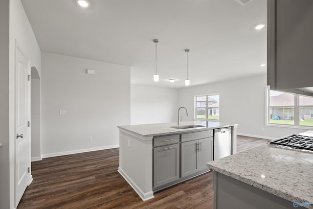 kitchen featuring gray cabinetry, light stone countertops, sink, an island with sink, and pendant lighting