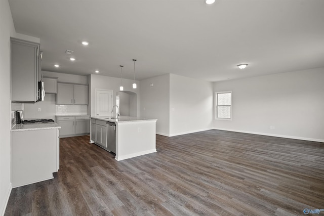 kitchen featuring decorative light fixtures, sink, gray cabinets, and an island with sink