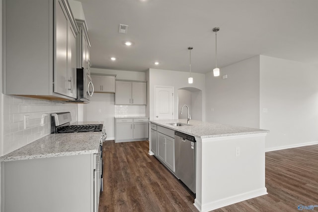 kitchen with stainless steel appliances, dark wood-type flooring, sink, a center island with sink, and hanging light fixtures