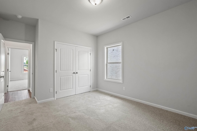 unfurnished bedroom with light carpet and a closet