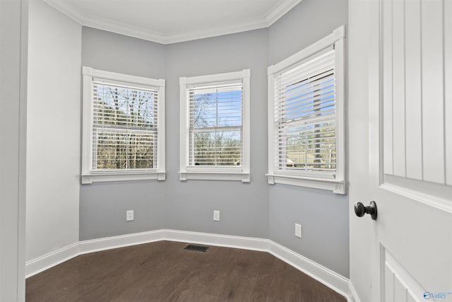 empty room with hardwood / wood-style flooring, a wealth of natural light, and ornamental molding