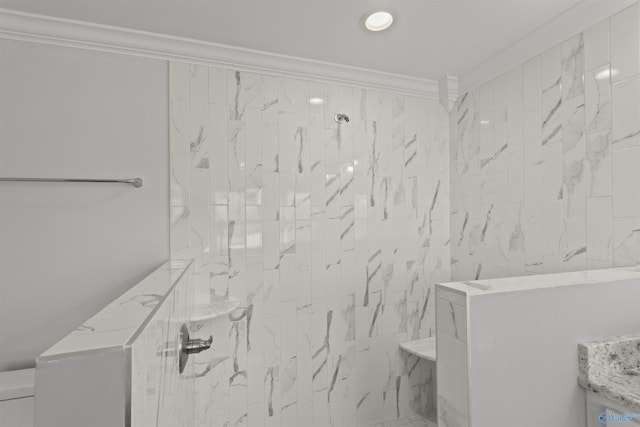 bathroom with toilet, crown molding, and a tile shower