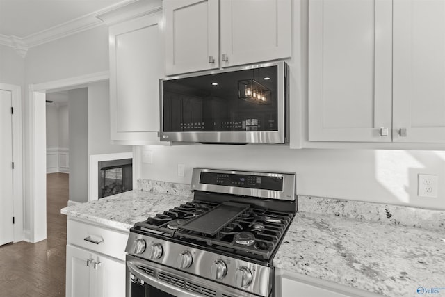 kitchen featuring ornamental molding, white cabinetry, light stone countertops, and appliances with stainless steel finishes