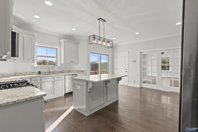 kitchen featuring stainless steel dishwasher, decorative light fixtures, sink, white cabinets, and a kitchen island