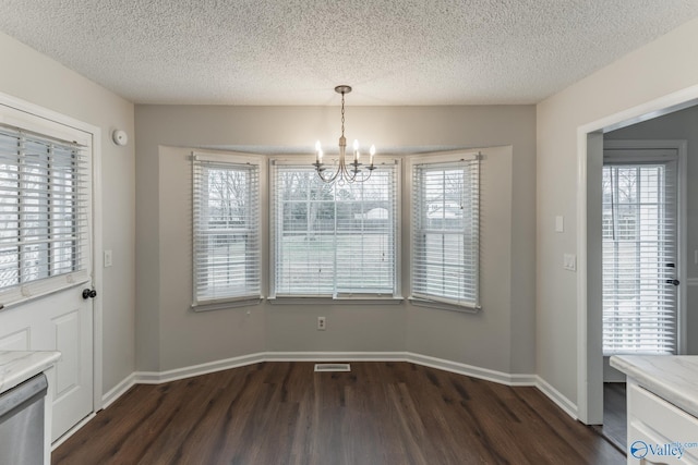 unfurnished dining area with a notable chandelier, a healthy amount of sunlight, dark wood-type flooring, and baseboards