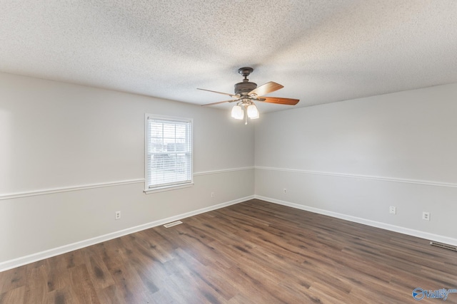 empty room featuring ceiling fan, dark wood-type flooring, and a textured ceiling