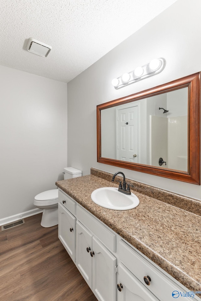 full bath with visible vents, toilet, vanity, wood finished floors, and a textured ceiling