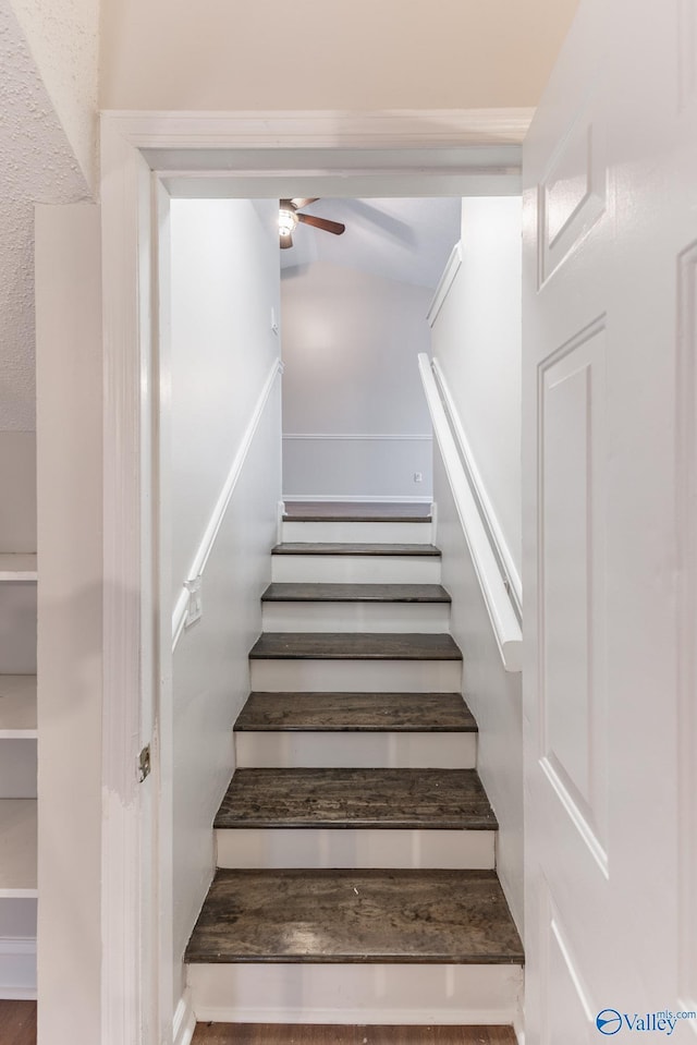 stairway featuring ceiling fan