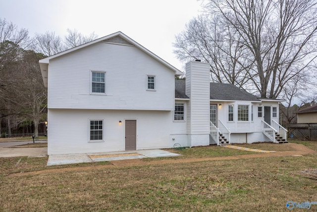 rear view of property featuring entry steps, a patio, a yard, and a chimney