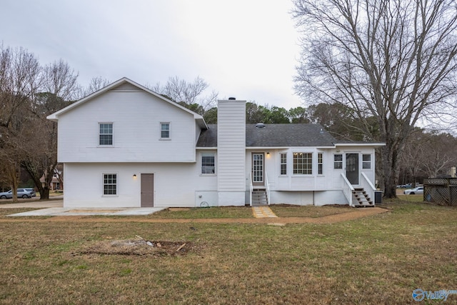 rear view of property featuring central air condition unit, entry steps, a yard, a chimney, and a patio area