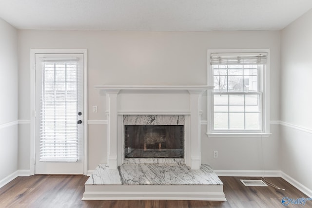 unfurnished living room featuring plenty of natural light, wood finished floors, and a premium fireplace