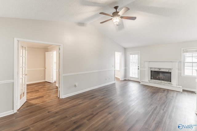 unfurnished living room with baseboards, ceiling fan, dark wood finished floors, vaulted ceiling, and a fireplace