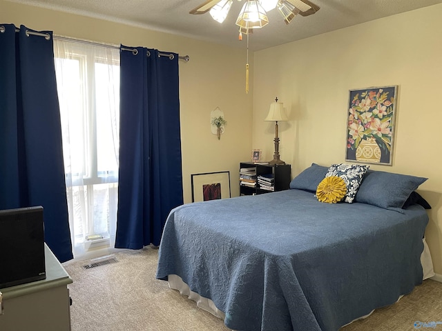 bedroom with ceiling fan, carpet flooring, and a textured ceiling