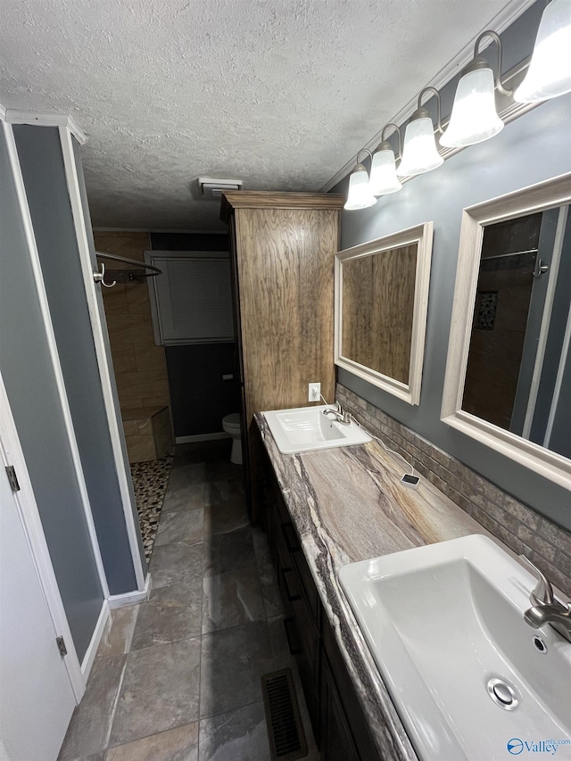 bathroom with visible vents, a tile shower, and a sink
