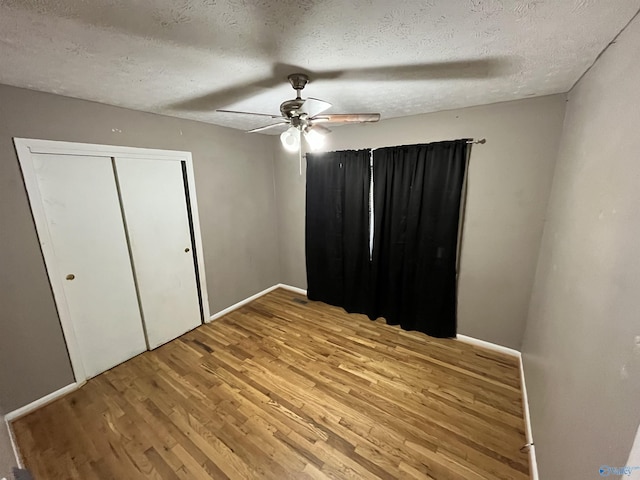 unfurnished bedroom with a closet, a textured ceiling, ceiling fan, and wood finished floors