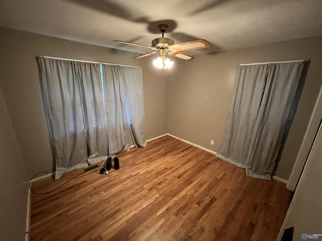 spare room with baseboards, a ceiling fan, and wood finished floors