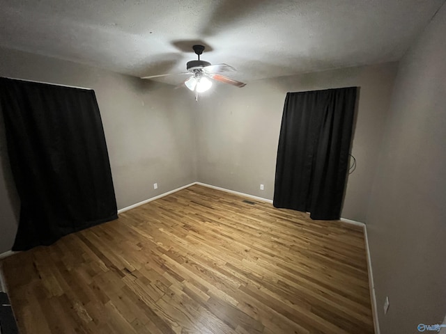 empty room with baseboards, a ceiling fan, and wood finished floors