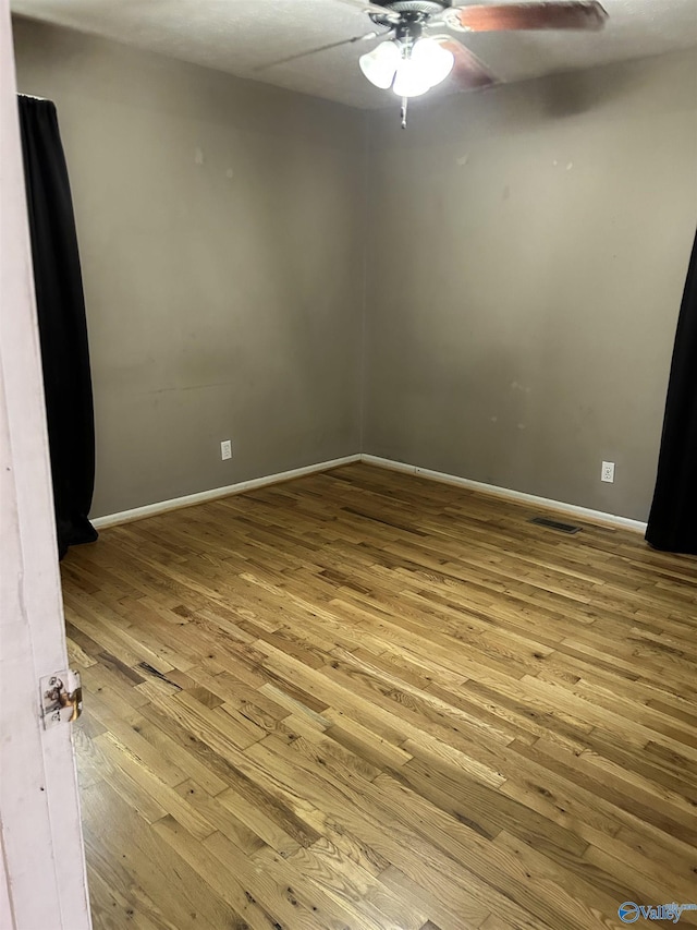unfurnished room featuring baseboards, ceiling fan, wood-type flooring, and visible vents