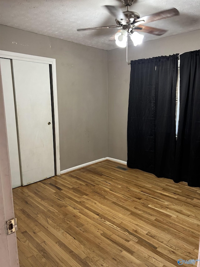 spare room featuring baseboards, a textured ceiling, ceiling fan, and wood finished floors