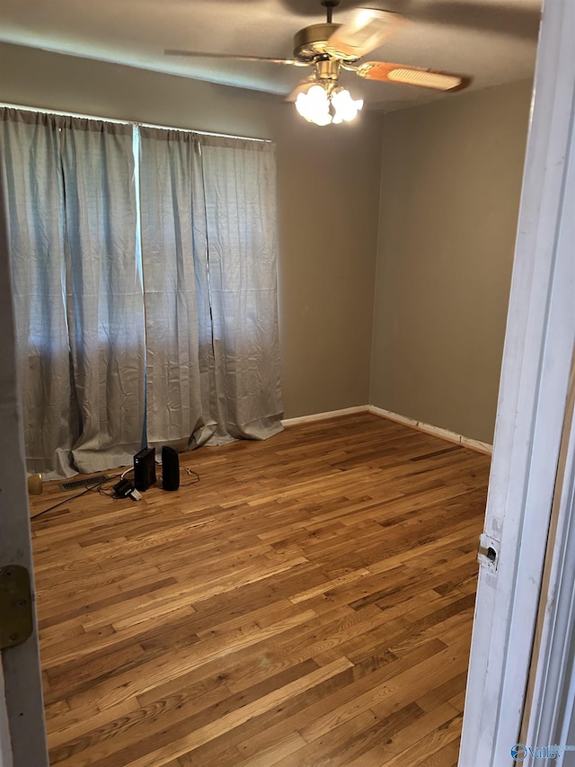 unfurnished room with a ceiling fan, baseboards, and wood finished floors