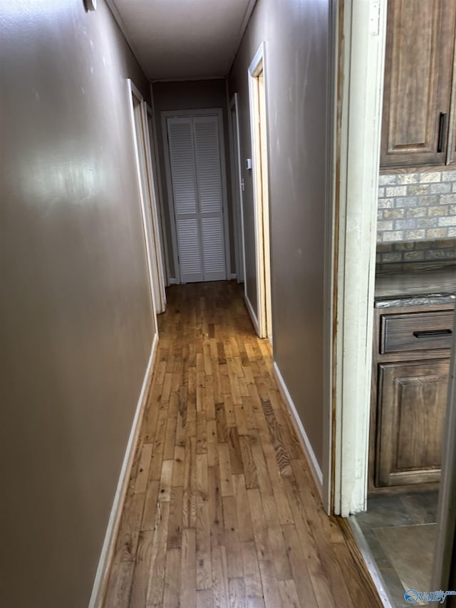 hallway featuring baseboards and hardwood / wood-style flooring